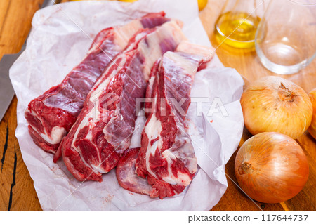 Fresh raw pork ribs with potatoes, onions and black pepper on wooden table 117644737