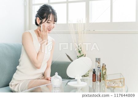 Asian woman applying lotion to skin with cotton Asian woman applying lotion to skin with cotton 117644809