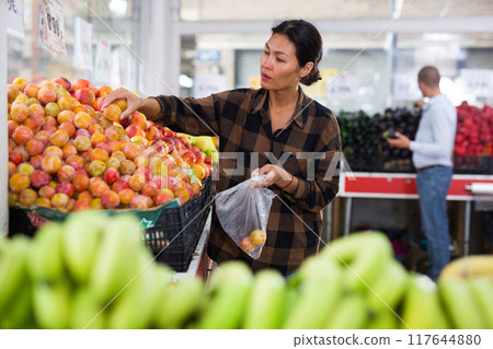 Asian woman choosing plums in supermarket 117644880