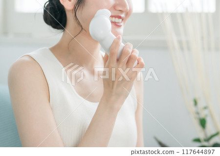 Young Asian woman washing her face with a facial cleansing brush Young Asian woman washing her face with a facial cleansing brush 117644897