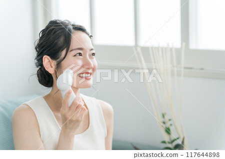 Young Asian woman washing her face with a facial cleansing brush Young Asian woman washing her face with a facial cleansing brush 117644898