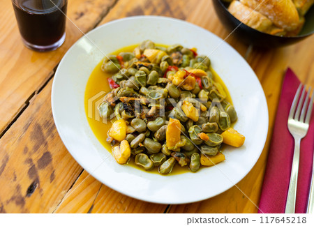 Plate contains portion of stewed beans with seafood, mussels, shrimps, and clams 117645218