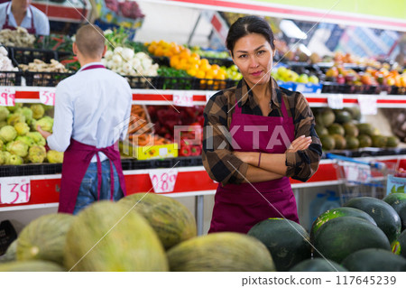 Woman presenting assortment in greengrocer Woman presenting assortment in greengrocer 117645239
