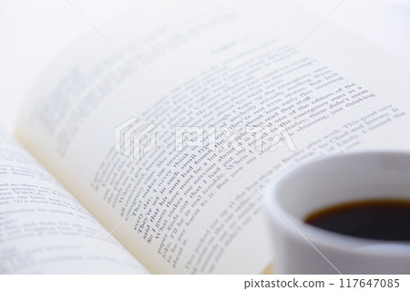 拿著一本打開的書(西洋書)和一個裝有咖啡的咖啡杯,一邊喝咖啡一邊享受閱讀的形象。 拿著一本打開的書(西洋書)和一個裝有咖啡的咖啡杯,一邊喝咖啡一邊享受閱讀的形象。 117647085