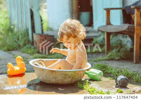 A little boy is bathing in a basin A little boy is bathing in a basin 117647404