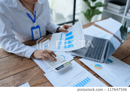 woman meticulously plans a finance audit, using a computer and calculator to review budget documents and ensure accuracy woman meticulously plans a finance audit, using a computer and calculator to review budget documents and ensure accuracy 117647506