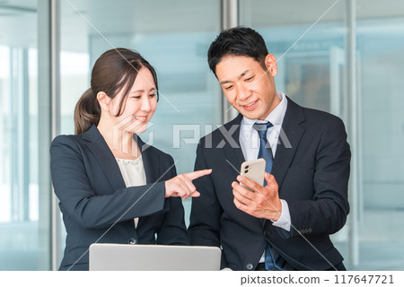 Businessman and businesswoman looking at smartphones during lunch break (smartphones, chatting, lunch break, topics) Businessman and businesswoman looking at smartphones during lunch break (smartphones, chatting, lunch break, topics) 117647721