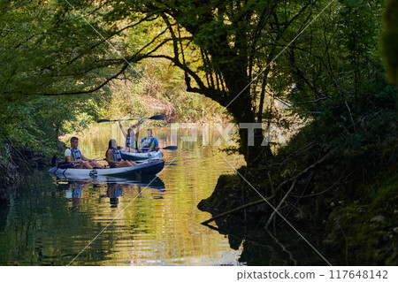 A group of friends enjoying having fun and kayaking while exploring the calm river, surrounding forest and large natural river canyons 117648142