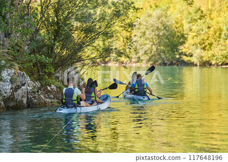 A group of friends enjoying having fun and kayaking while exploring the calm river, surrounding forest and large natural river canyons 117648196