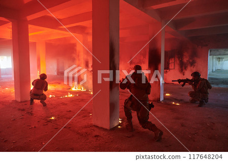 A group of professional soldiers bravely executes a dangerous rescue mission, surrounded by fire in a perilous building. 117648204