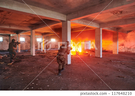A group of professional soldiers bravely executes a dangerous rescue mission, surrounded by fire in a perilous building. 117648210