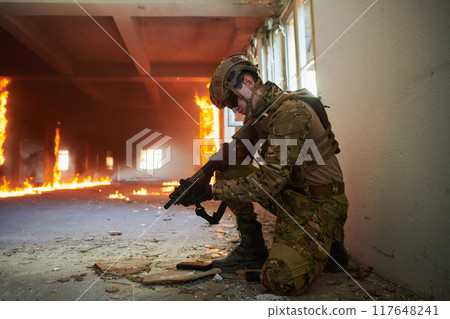 Soldier in action near window changing magazine and take cover Soldier in action near window changing magazine and take cover 117648241