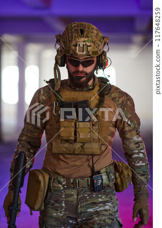 A professional soldier undertakes a perilous mission in an abandoned building illuminated by neon blue and purple lights A professional soldier undertakes a perilous mission in an abandoned building illuminated by neon blue and purple lights 117648259