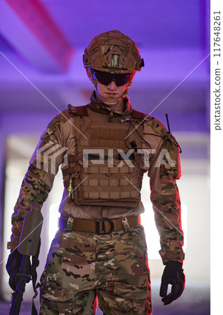 A professional soldier undertakes a perilous mission in an abandoned building illuminated by neon blue and purple lights 117648261