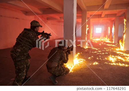 A group of professional soldiers bravely executes a dangerous rescue mission, surrounded by fire in a perilous building. 117648291