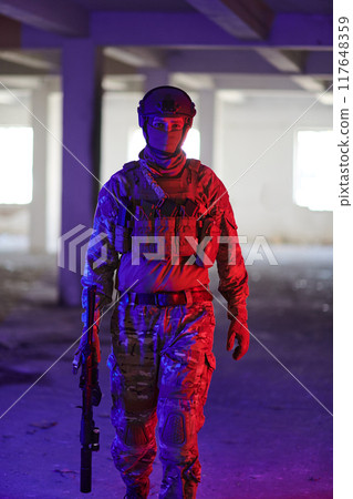 A professional soldier undertakes a perilous mission in an abandoned building illuminated by neon blue and purple lights 117648359