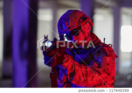 A professional soldier undertakes a perilous mission in an abandoned building illuminated by neon blue and purple lights 117648390