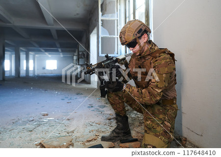 Soldier in action near window changing magazine and take cover Soldier in action near window changing magazine and take cover 117648410