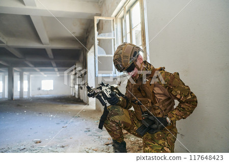 Soldier in action near window changing magazine and take cover Soldier in action near window changing magazine and take cover 117648423