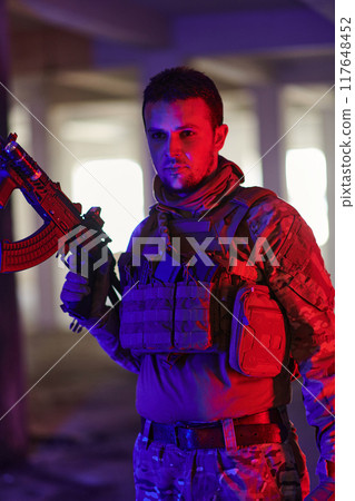 A professional soldier undertakes a perilous mission in an abandoned building illuminated by neon blue and purple lights 117648452