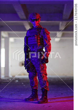 A professional soldier undertakes a perilous mission in an abandoned building illuminated by neon blue and purple lights A professional soldier undertakes a perilous mission in an abandoned building illuminated by neon blue and purple lights 117648496