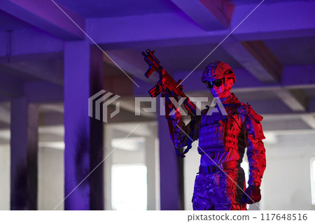 A professional soldier undertakes a perilous mission in an abandoned building illuminated by neon blue and purple lights A professional soldier undertakes a perilous mission in an abandoned building illuminated by neon blue and purple lights 117648516