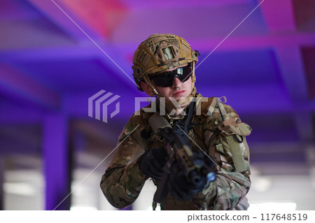 A professional soldier undertakes a perilous mission in an abandoned building illuminated by neon blue and purple lights 117648519