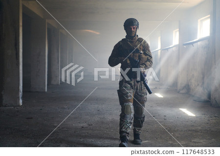 A professional soldier in an abandoned building shows courage and determination in a war campaign 117648533