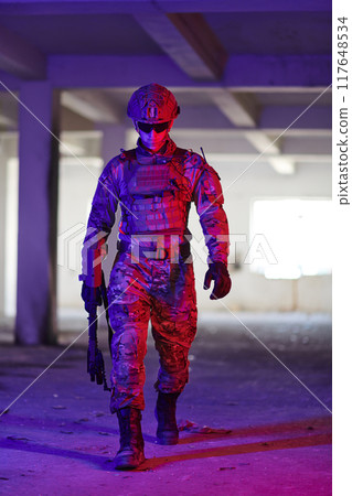 A professional soldier undertakes a perilous mission in an abandoned building illuminated by neon blue and purple lights 117648534