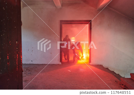 A group of professional soldiers bravely executes a dangerous rescue mission, surrounded by fire in a perilous building. A group of professional soldiers bravely executes a dangerous rescue mission, surrounded by fire in a perilous building. 117648551