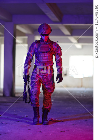 A professional soldier undertakes a perilous mission in an abandoned building illuminated by neon blue and purple lights A professional soldier undertakes a perilous mission in an abandoned building illuminated by neon blue and purple lights 117648560
