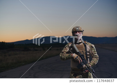 A professional soldier in full military gear striding through the dark night as he embarks on a perilous military mission 117648637