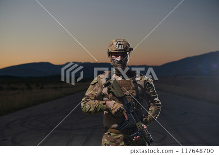 A professional soldier in full military gear striding through the dark night as he embarks on a perilous military mission 117648700