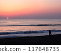 Two people on the beach with the sun setting on the horizon 117648735