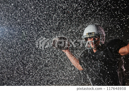 American Football Field: Lonely Athlete Warrior Standing on a Field Holds his Helmet and Ready to Play. Player Preparing to Run, Attack and Score Touchdown. Rainy Night with Dramatic Fog, Blue Light 117648938