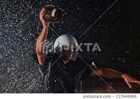 American Football Field: Lonely Athlete Warrior Standing on a Field Holds his Helmet and Ready to Play. Player Preparing to Run, Attack and Score Touchdown. Rainy Night with Dramatic Fog, Blue Light 117648966