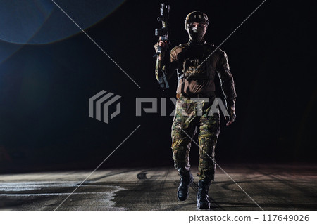 A professional soldier in full military gear striding through the dark night as he embarks on a perilous military mission A professional soldier in full military gear striding through the dark night as he embarks on a perilous military mission 117649026