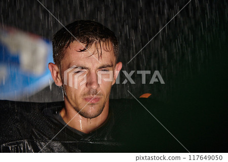 American Football Field: Lonely Athlete Warrior Standing on a Field Holds his Helmet and Ready to Play. Player Preparing to Run, Attack and Score Touchdown. Rainy Night with Dramatic Fog, Blue Light 117649050