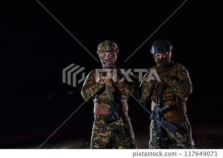 Two professional soldiers marching through the dark of night on a dangerous mission, epitomizing their unwavering bravery, unwavering teamwork, and the high-stakes intensity of their specialized 117649071