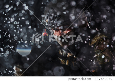 Army soldier in Combat Uniforms with an assault rifle, plate carrier and combat helmet going on a dangerous mission on a rainy night. Army soldier in Combat Uniforms with an assault rifle, plate carrier and combat helmet going on a dangerous mission on a rainy night. 117649079
