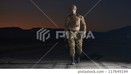 A professional soldier in full military gear striding through the dark night as he embarks on a perilous military mission 117649194