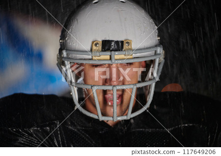 American Football Field: Lonely Athlete Warrior Standing on a Field Holds his Helmet and Ready to Play. Player Preparing to Run, Attack and Score Touchdown. Rainy Night with Dramatic Fog, Blue Light American Football Field: Lonely Athlete Warrior Standing on a Field Holds his Helmet and Ready to Play. Player Preparing to Run, Attack and Score Touchdown. Rainy Night with Dramatic Fog, Blue Light 117649206
