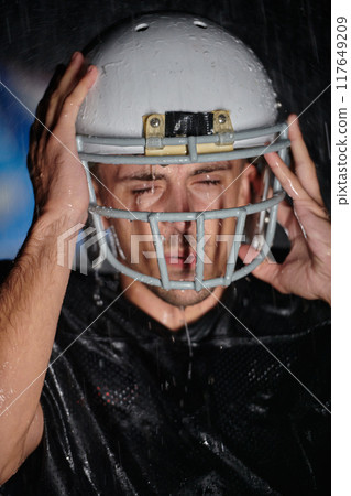 American Football Field: Lonely Athlete Warrior Standing on a Field Holds his Helmet and Ready to Play. Player Preparing to Run, Attack and Score Touchdown. Rainy Night with Dramatic Fog, Blue Light American Football Field: Lonely Athlete Warrior Standing on a Field Holds his Helmet and Ready to Play. Player Preparing to Run, Attack and Score Touchdown. Rainy Night with Dramatic Fog, Blue Light 117649209