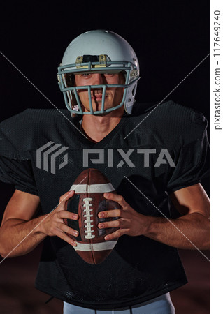 American Football Field: Lonely Athlete Warrior Standing on a Field Holds his Helmet and Ready to Play. Player Preparing to Run, Attack and Score Touchdown. 117649240