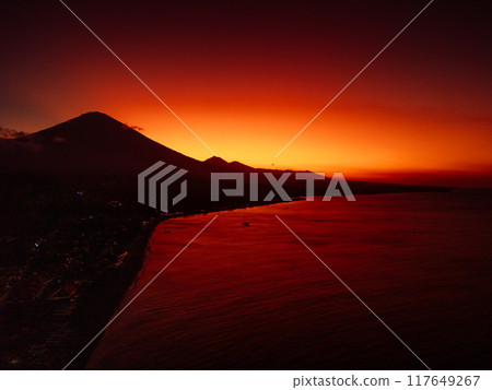 Coastline with sunset and quiet ocean in Bali. Silhouette of coastline with Agung volcano Coastline with sunset and quiet ocean in Bali. Silhouette of coastline with Agung volcano 117649267