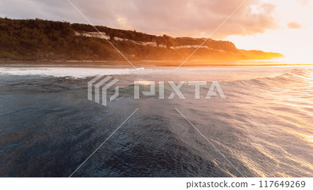Bali coastline, ocean on low tide and waves with sunrise. Panoramic drone view Bali coastline, ocean on low tide and waves with sunrise. Panoramic drone view 117649269