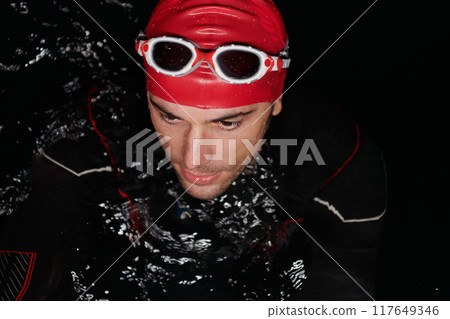Authentic triathlete swimmer having a break during hard training on night 117649346
