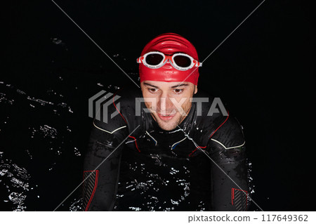 Authentic triathlete swimmer having a break during hard training on night Authentic triathlete swimmer having a break during hard training on night 117649362