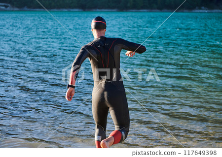 Triathlon athlete starting swimming training on lake 117649398