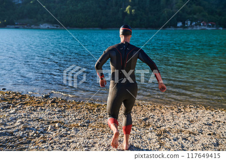 Triathlon athlete starting swimming training on lake 117649415